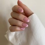 person with pink manicure on white textile